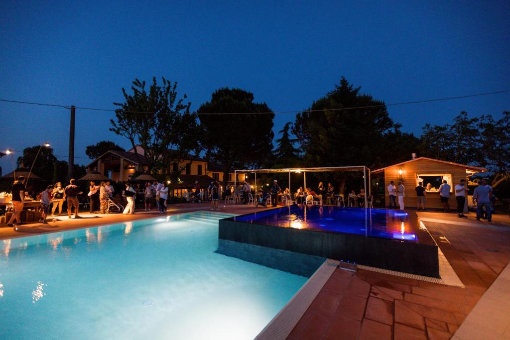 una piscina por la noche con gente sentada alrededor en Agriturismo Trerè, en Faenza