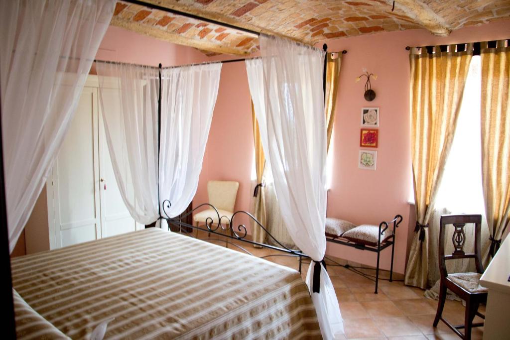 a bedroom with a bed and curtains and a couch at Agriturismo Monbertola in Govone