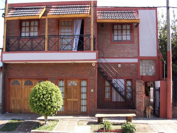 a red brick house with a dog in front of it at Complejo La Naranjita in Rosario