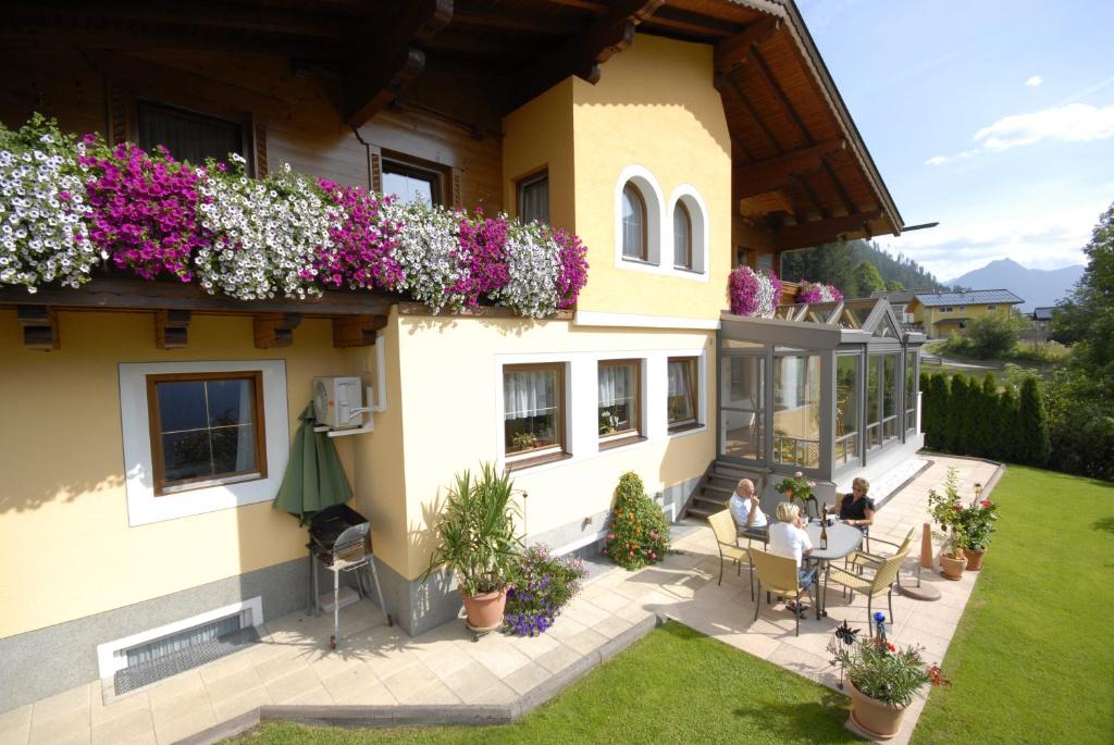 personnes assises à une table à l'extérieur d'une maison avec des fleurs dans l'établissement Haus Silvia, à Flachau