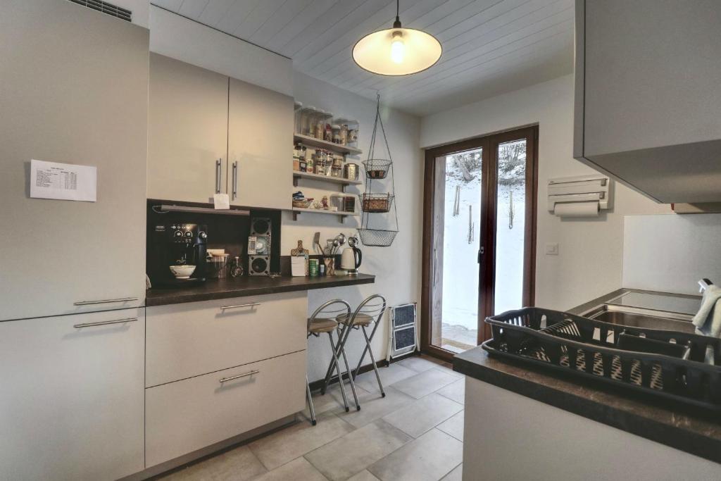 cocina con armarios blancos y encimera en Modern and well equipped apartment, 500m from the 4 Vallées ski area, en Agettes