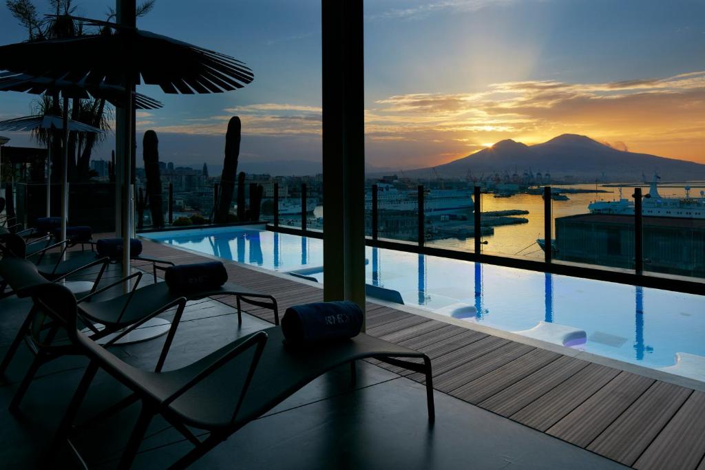 a swimming pool with chairs and a view of a mountain at ROMEO Napoli in Naples