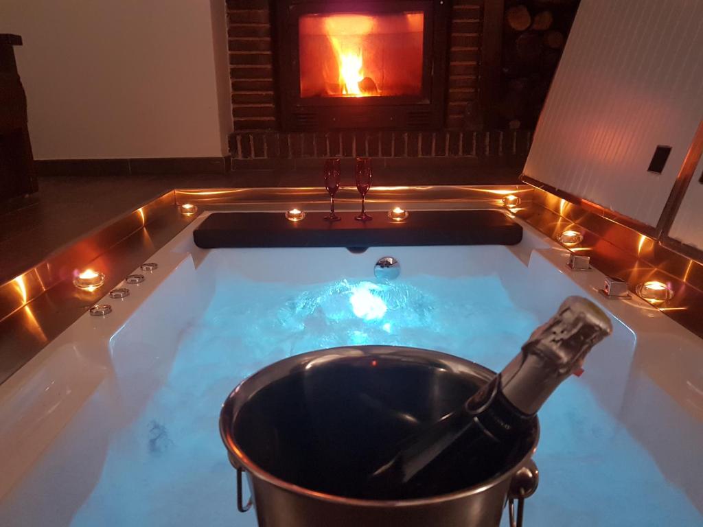 a bathtub with a bottle of champagne in it with a fireplace at Casa Spa El Capricho de Miguel in Babilafuente