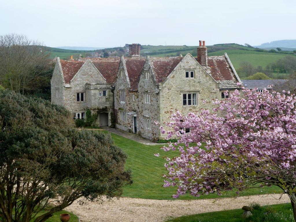 an old stone house with pink flowers in front of it at Westcourt Farm in Shorwell