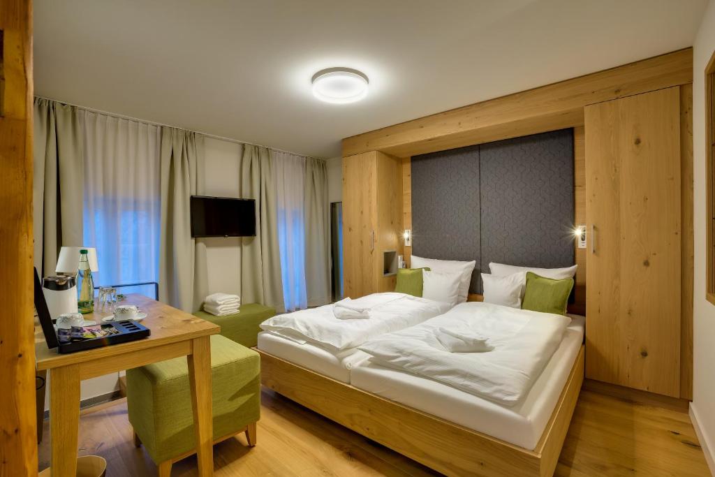 ein Hotelzimmer mit einem Bett, einem Tisch und einem Schreibtisch in der Unterkunft Boutique Hotel grüner Zweig in Schlettau