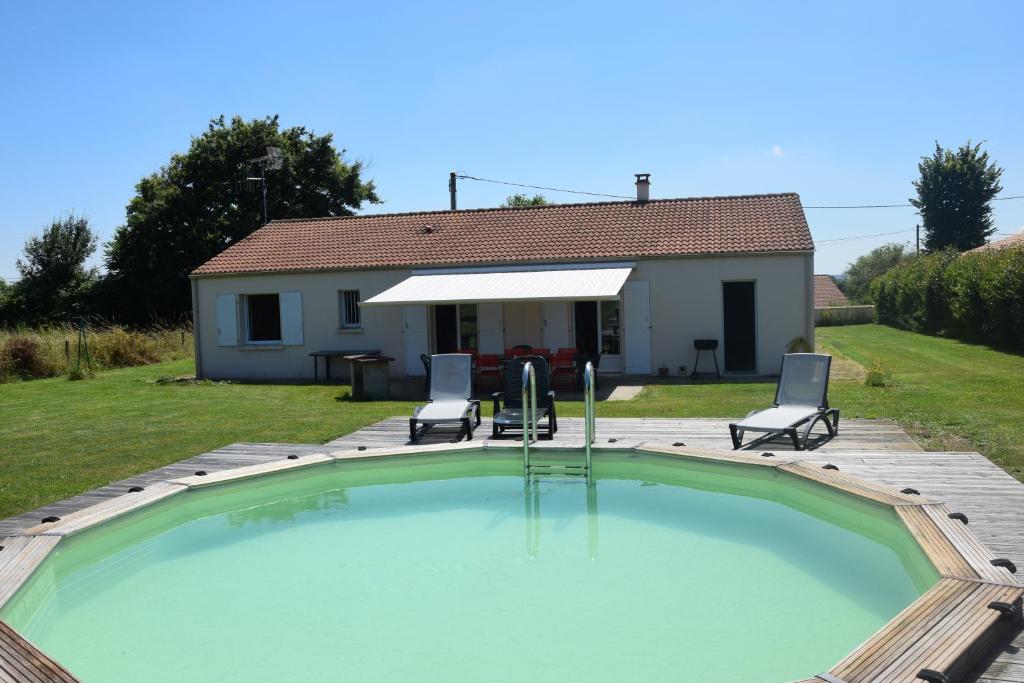 ein Swimmingpool mit zwei Stühlen und einem Haus in der Unterkunft Le HAMEAU 1936 Gîte des Milanaïs in Cherveux
