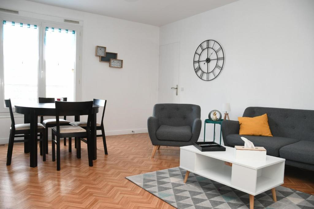 a living room with a couch and a table and chairs at Appartement Le Grand Parc in Châteauroux