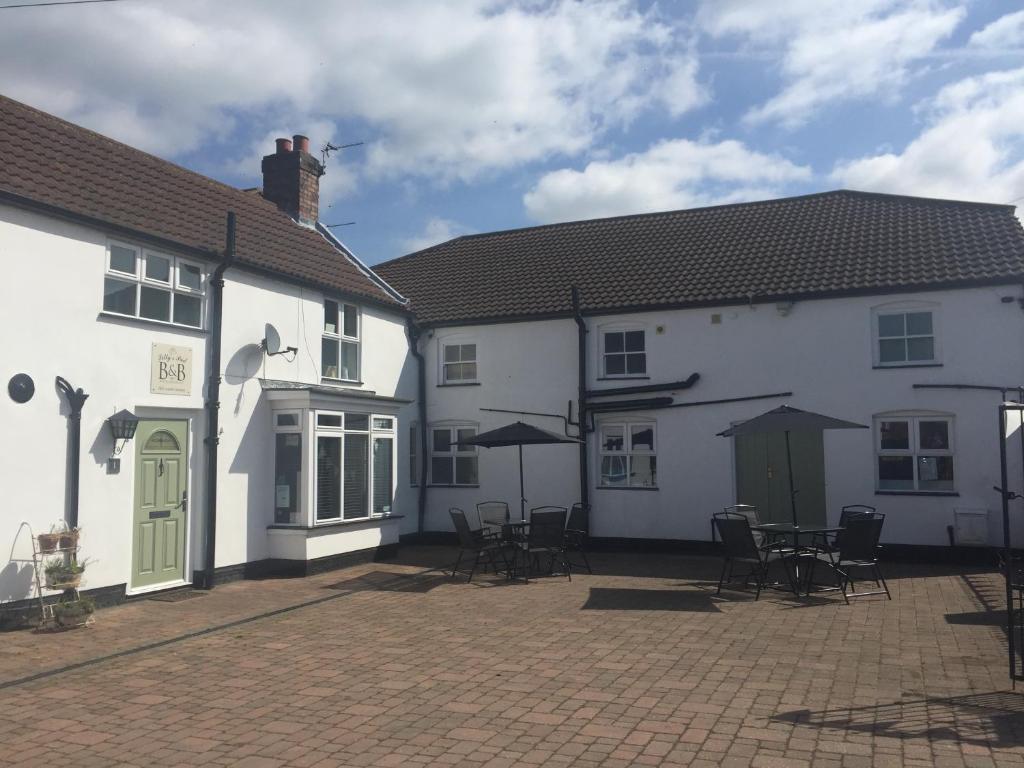 a group of white buildings with tables and chairs at Lilly's Pad in Keelby