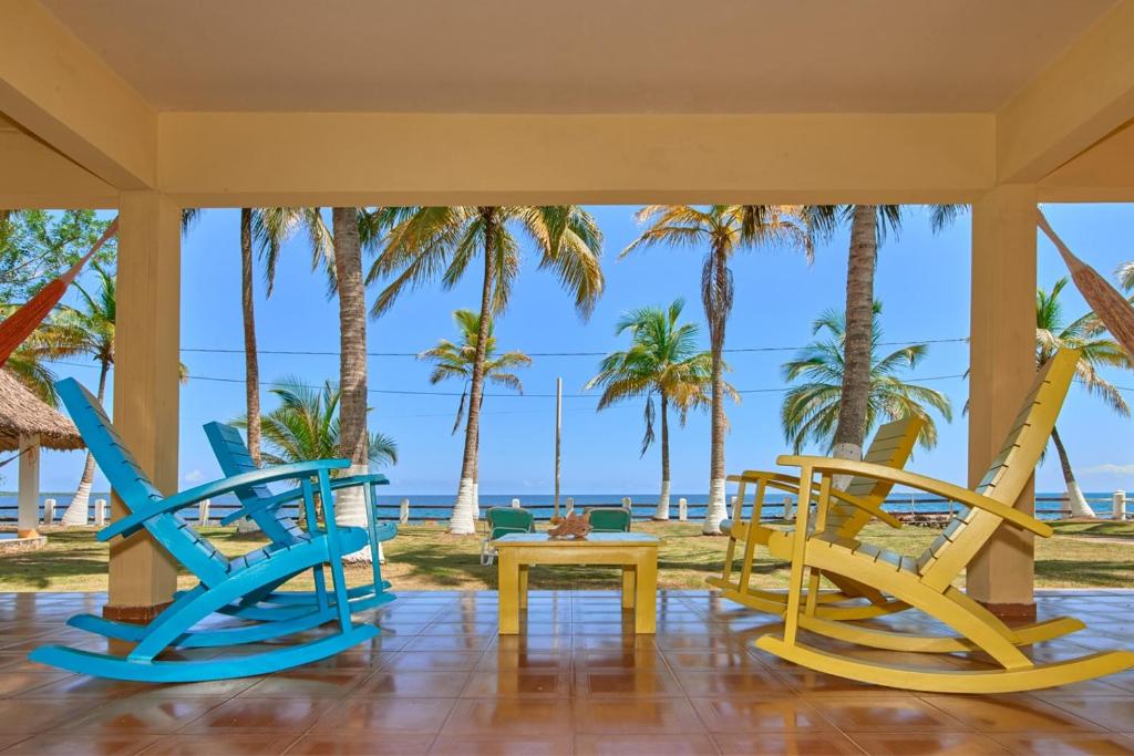een kamer met stoelen en een tafel en palmbomen bij Cabaña El Refugio in San Antero