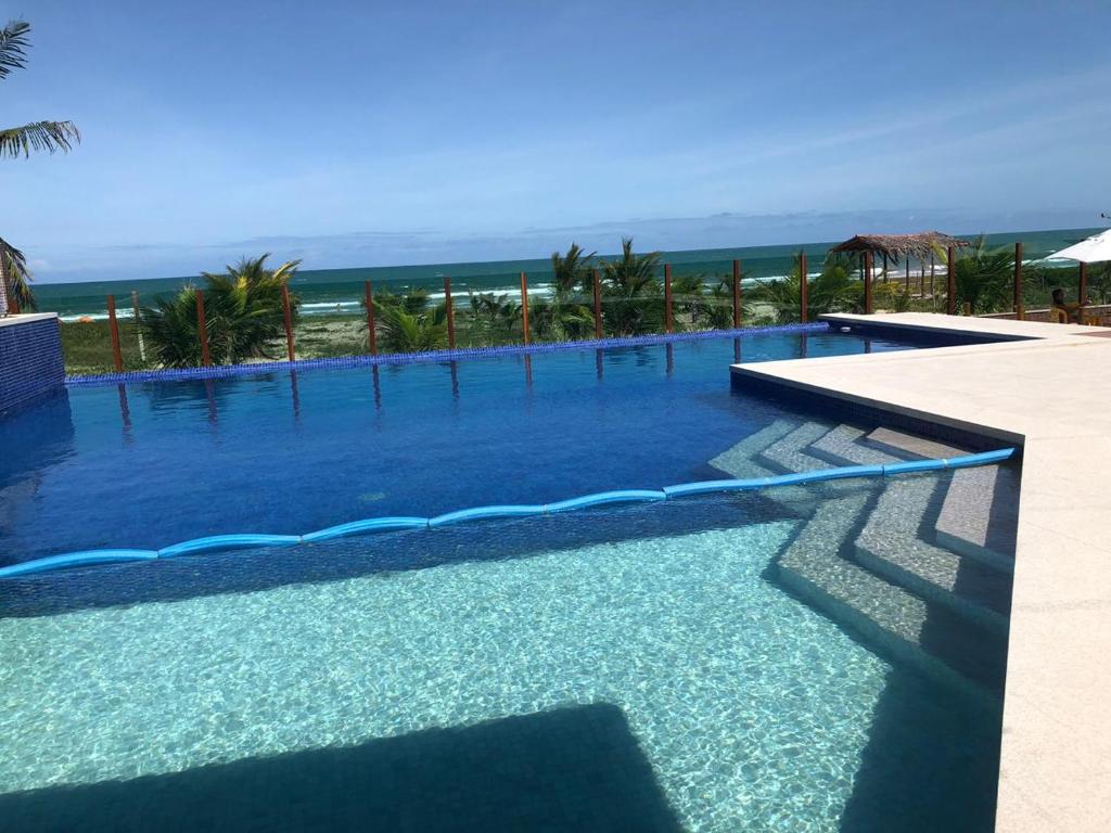 a large swimming pool with the ocean in the background at Gabrielly Praia Hotel in Guaibim