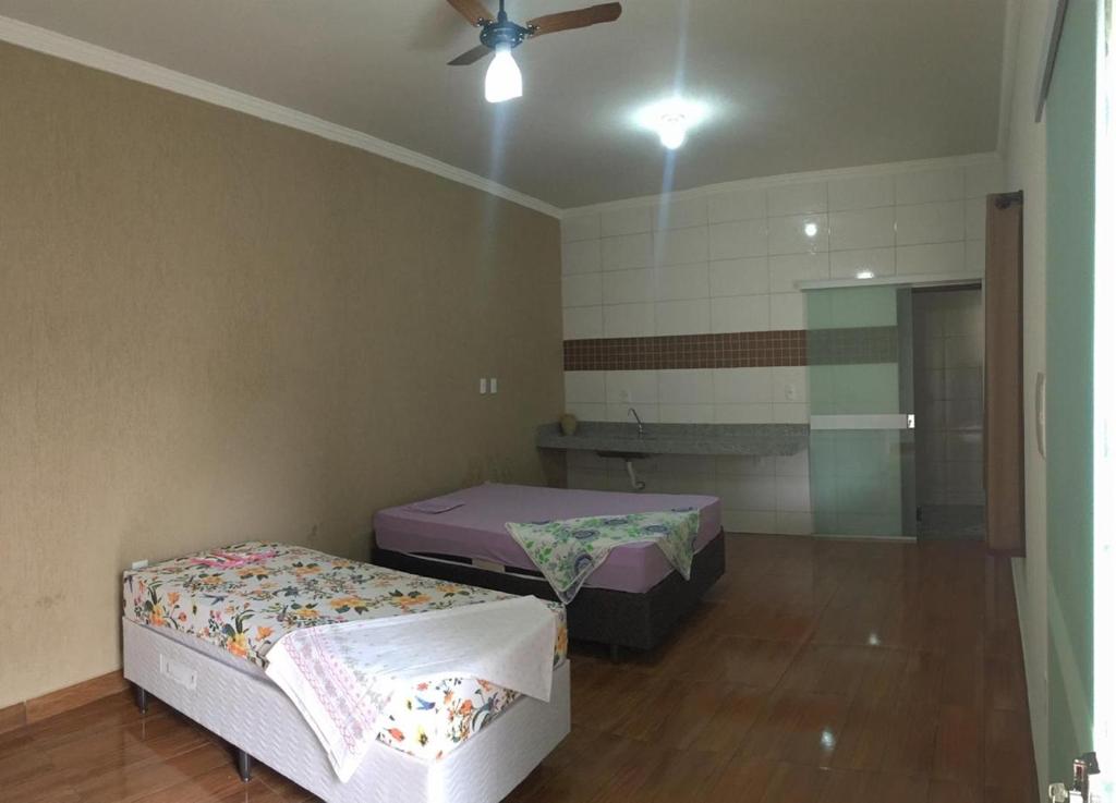 a room with two beds and a ceiling fan at Bom Jardim in Piumhi