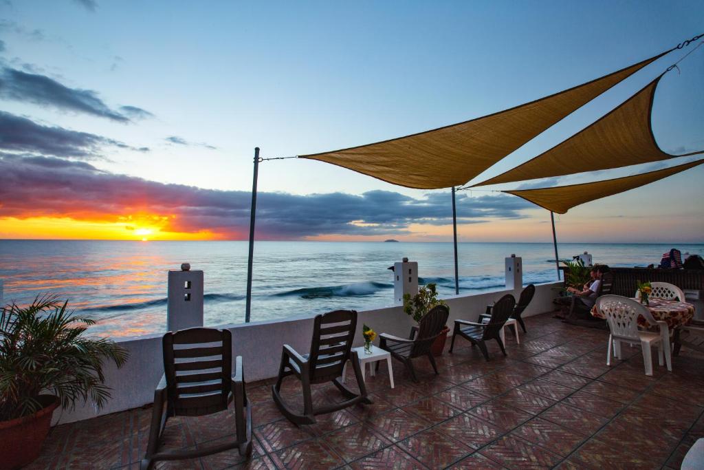 een patio met stoelen en tafels en de oceaan bij zonsondergang bij Coconut Palms Inn in Rincon