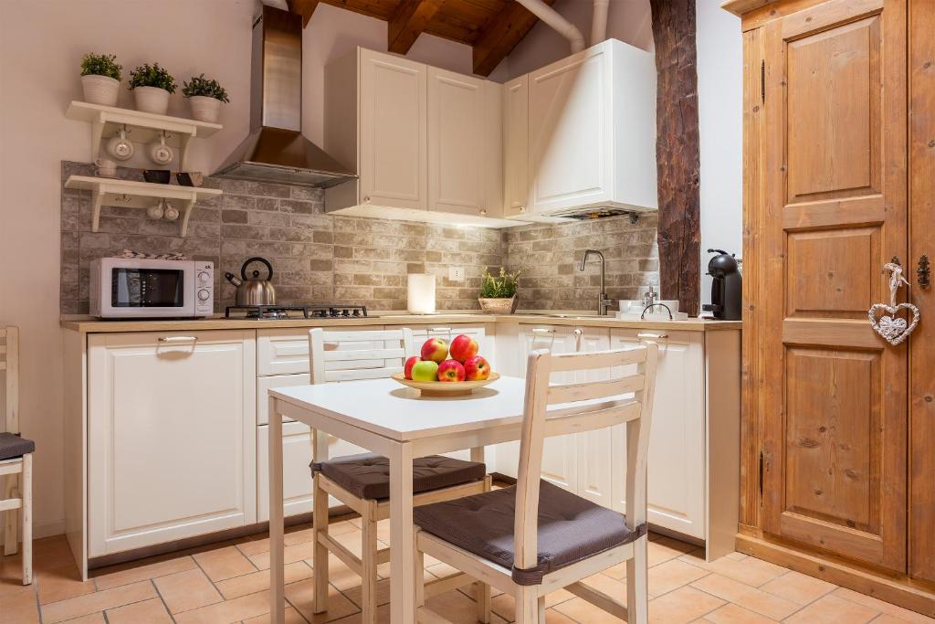 una cucina con armadi bianchi e un tavolo con frutta di T-Rooftop a Como