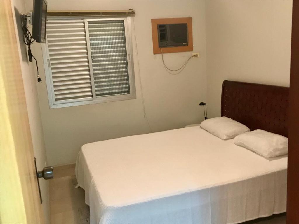 Habitación pequeña con cama y ventana en Apartamento Nota 10, en Guarujá
