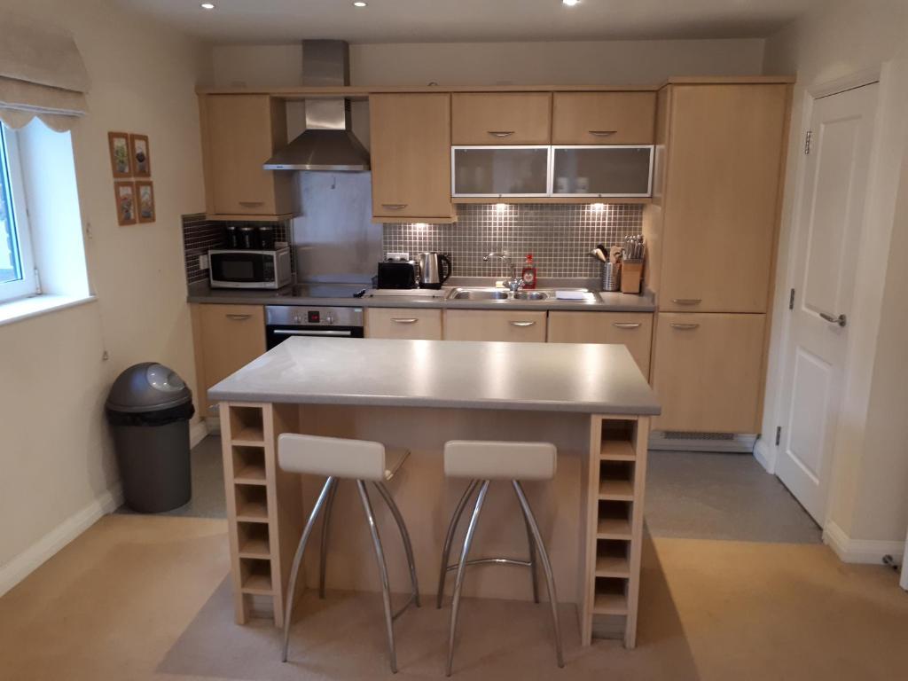 a kitchen with a large island with two bar stools at Solihull centre apartments in Solihull