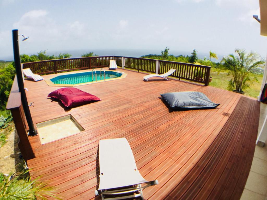 una terraza de madera con piscina en una casa en OBED, en Grand-Bourg