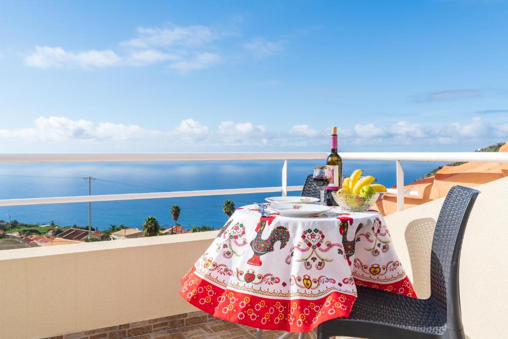 - une table avec une bouteille de vin et des fruits sur un balcon dans l'établissement Apartment lucy, à Arco da Calheta