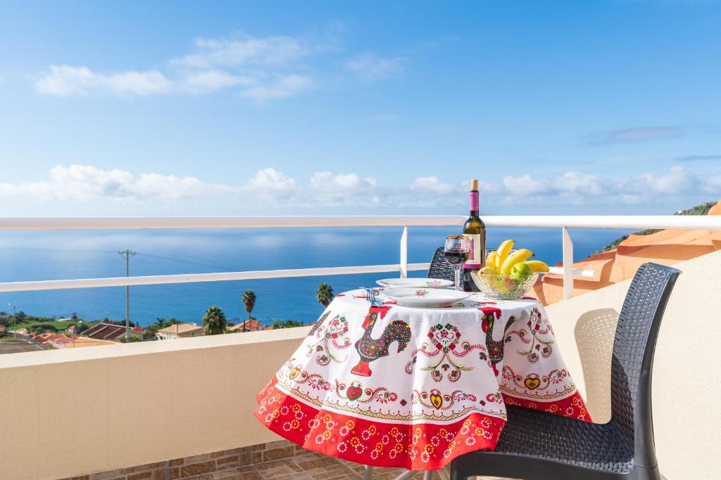 een tafel met een fles wijn en fruit op een balkon bij Apartment lucy in Arco da Calheta