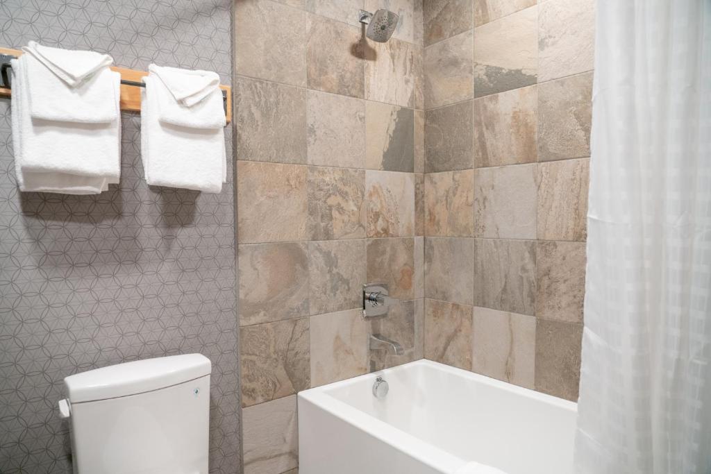 a bathroom with a tub and a toilet and a sink at Banff Rocky Mountain Resort in Banff