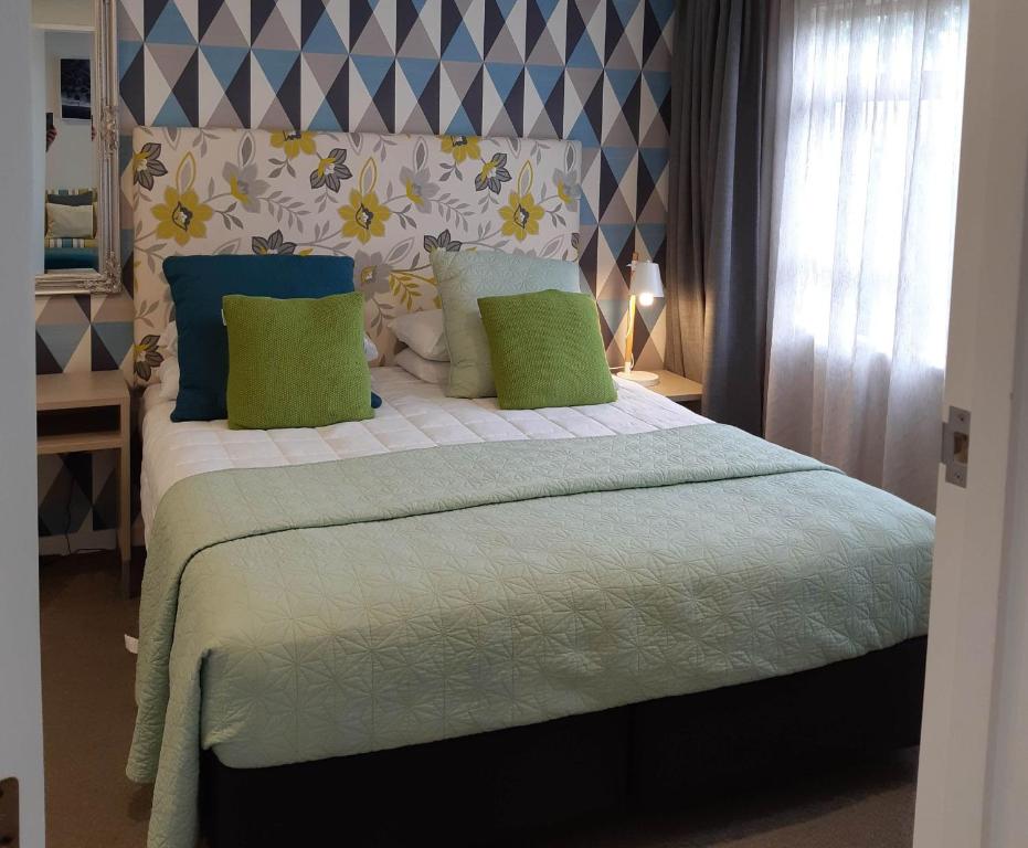 a bedroom with a bed with green and blue pillows at ASURE Destiny on Fitzherbert Motel in Palmerston North