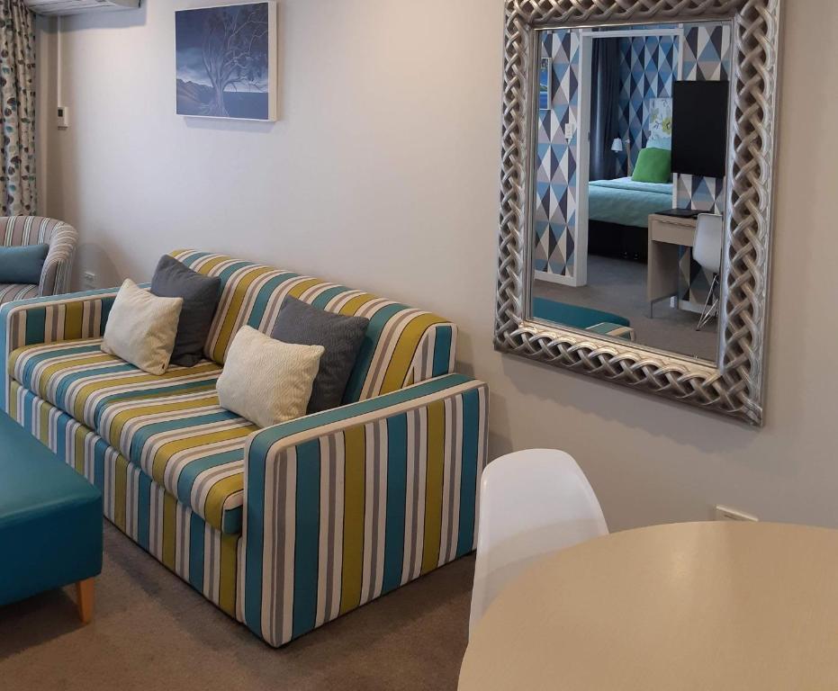 a living room with a couch and a mirror at ASURE Destiny on Fitzherbert Motel in Palmerston North
