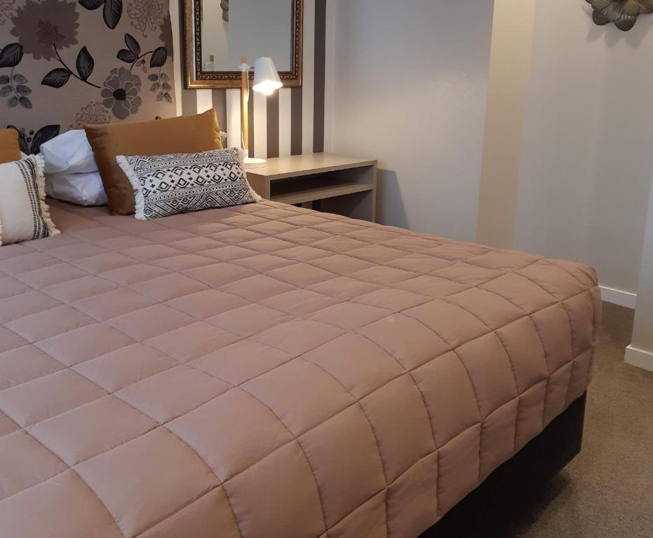 a large pink bed in a room with a table at ASURE Destiny on Fitzherbert Motel in Palmerston North