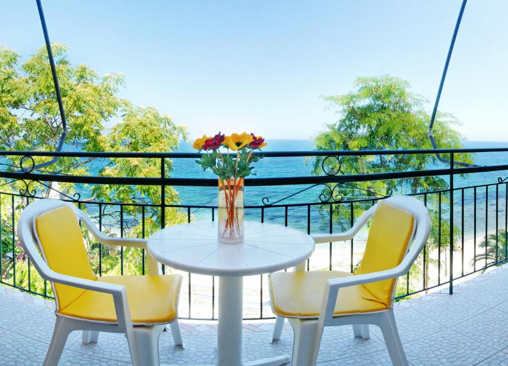 uma mesa com duas cadeiras e um vaso de flores numa varanda em Empress Corfu em Perama