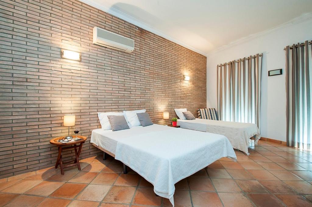 a bedroom with two beds and a brick wall at Turismo Guadiana - Casas in Mértola