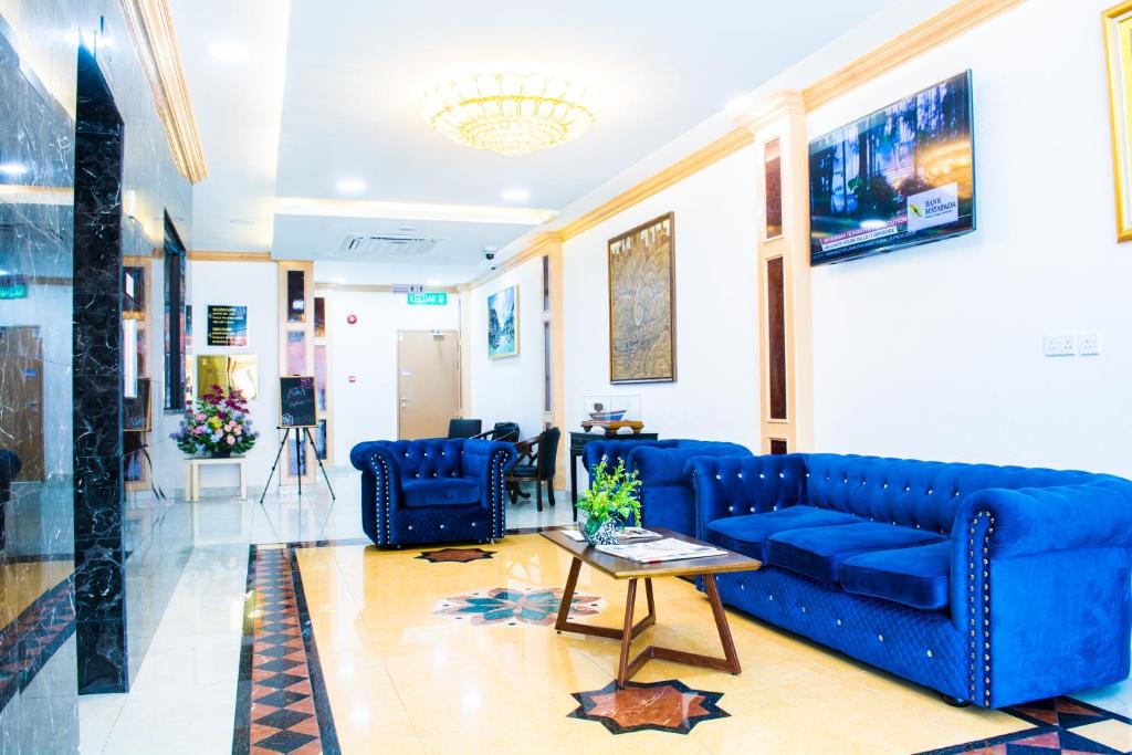 a living room with blue couches and a table at Al Afiah Hotel in Bandar Seri Begawan