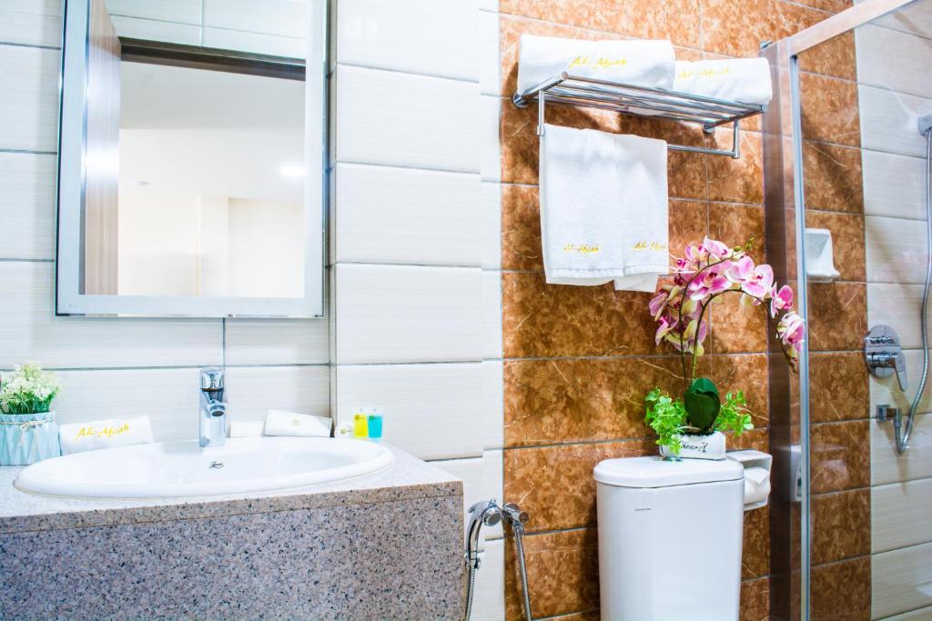 a bathroom with a sink and a toilet and a mirror at Al Afiah Hotel in Bandar Seri Begawan