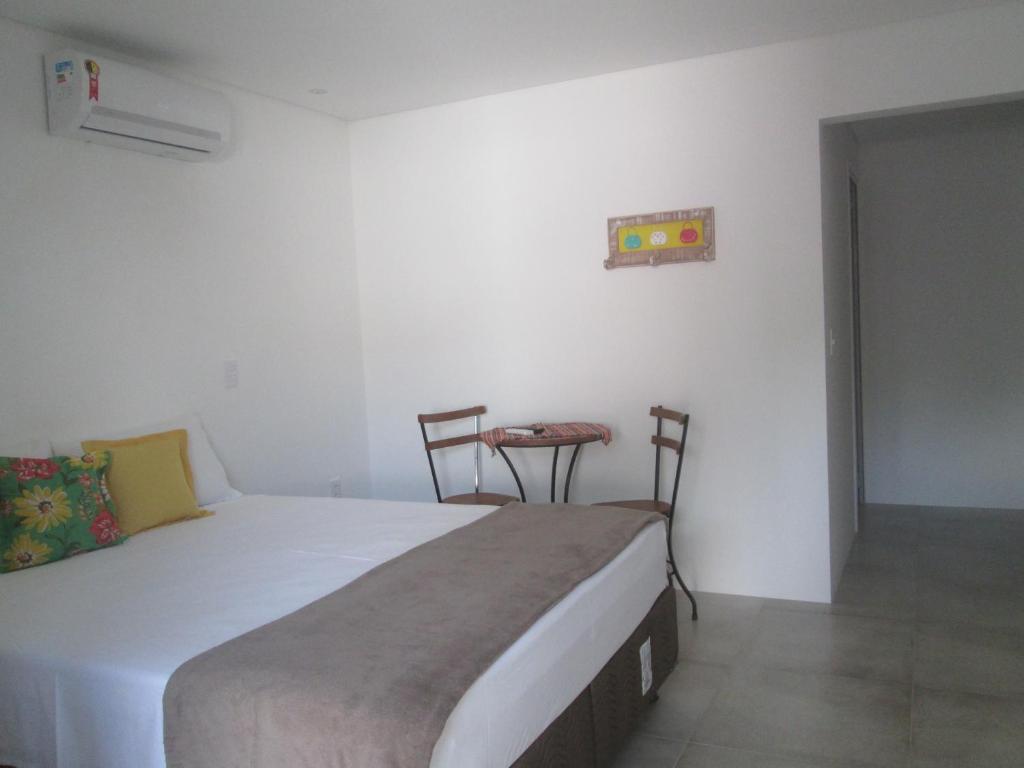 a bedroom with a bed with two chairs and a table at Pontal Flats in Paraty