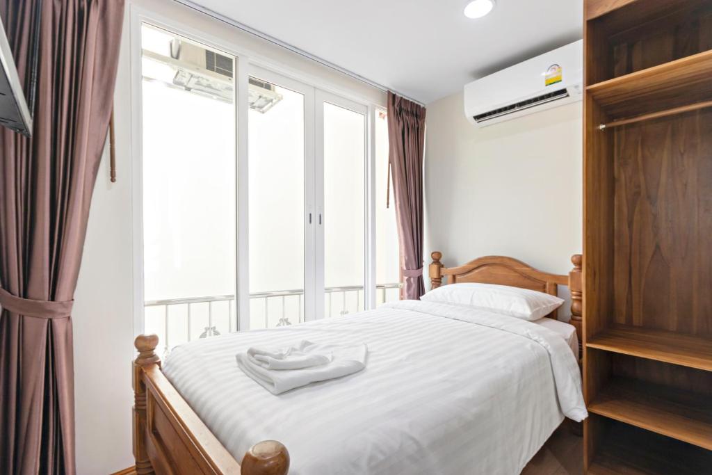 a bedroom with a bed with white sheets and a window at Royale 8 Ville Guest House in Bangkok