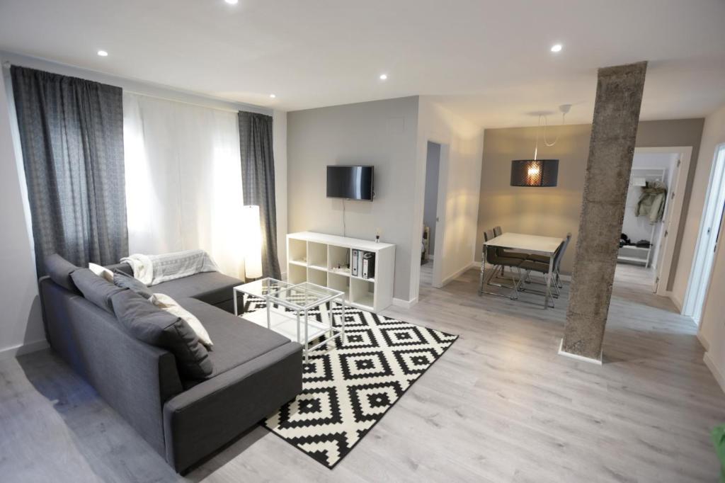 ein Wohnzimmer mit einem Sofa und einem Tisch in der Unterkunft Brand new charming apartment next to the river in Sevilla