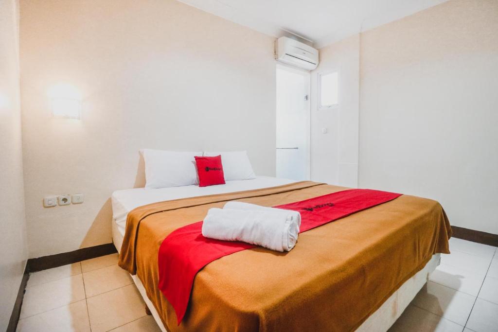 1 dormitorio con 1 cama grande con sábanas rojas y blancas en RedDoorz @ Pandu Raya Bogor, en Bogor