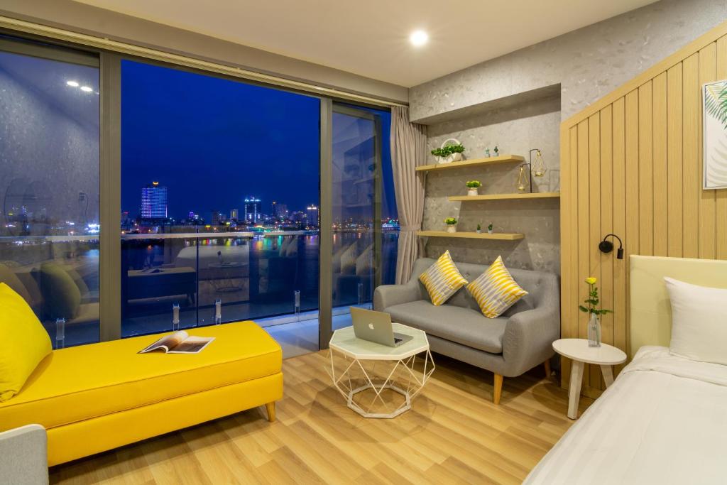 a bedroom with a bed and a couch and a window at Happy Day Riverside Hotel & Spa Danang by Haviland in Danang