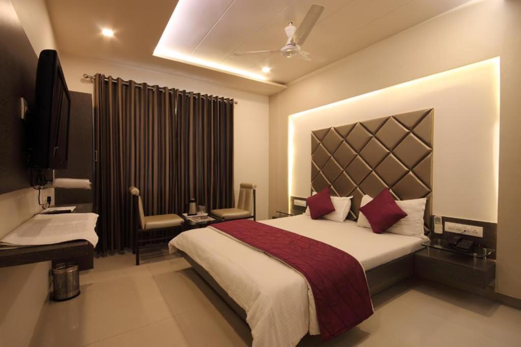 a hotel room with a large bed and a desk at Hotel Flair Inn in Ahmedabad