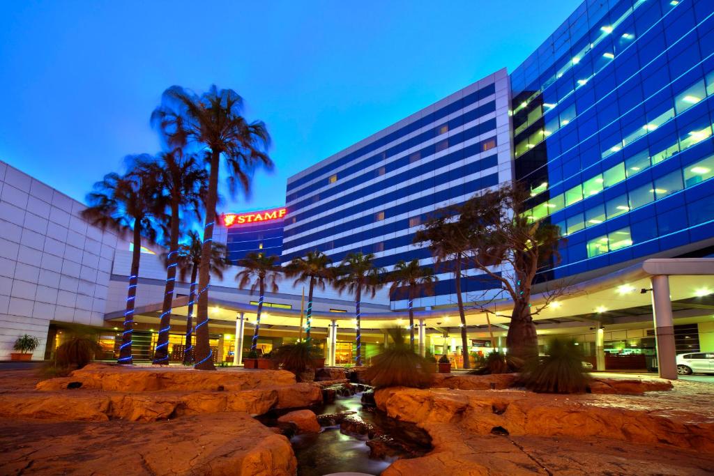 Stamford Plaza Sydney Airport Hotel & Conference Centre في سيدني: فندق فيه نخل امام مبنى