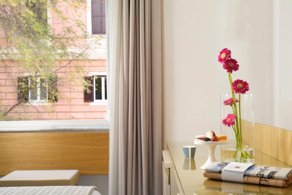 Pokój z oknem z wazą z kwiatami na stole w obiekcie Magica Luna Boutique Hotel - Roma w Rzymie