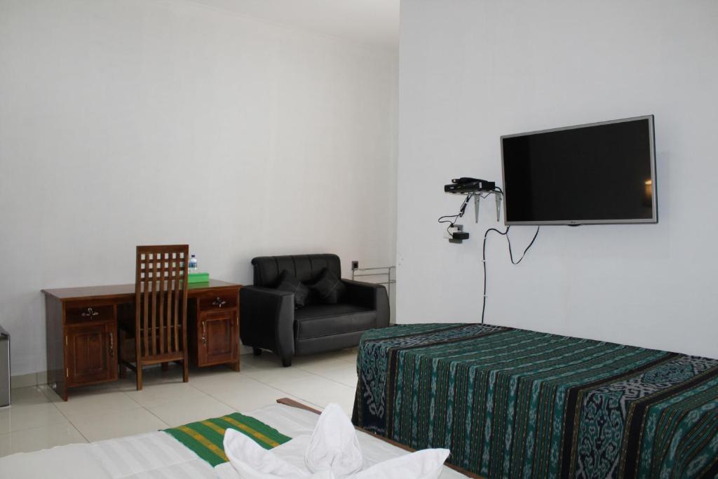 a living room with a tv and a couch and a chair at Hotel Green Prundi in Labuan Bajo