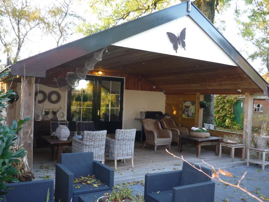 eine Terrasse mit Markise, Stühlen und einem Tisch in der Unterkunft gastenverblijf Ebbenbroek in Bruchterveld