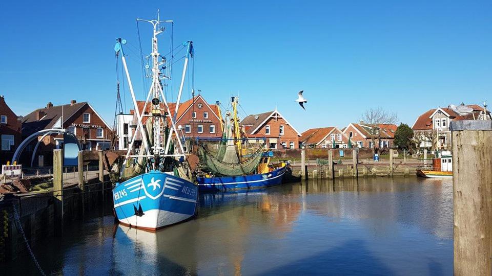 three boats are docked in a harbor with houses at Ferienwohnung "Kleine Krabbe" in Werdum