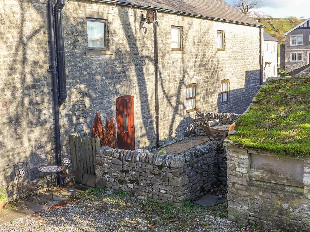 a stone house with a red door and a stone wall at 2 Primitive Mews in Chelmorton