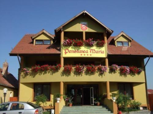 a building with a sign for a restaurant with flowers at Pension Maria in Sibiu