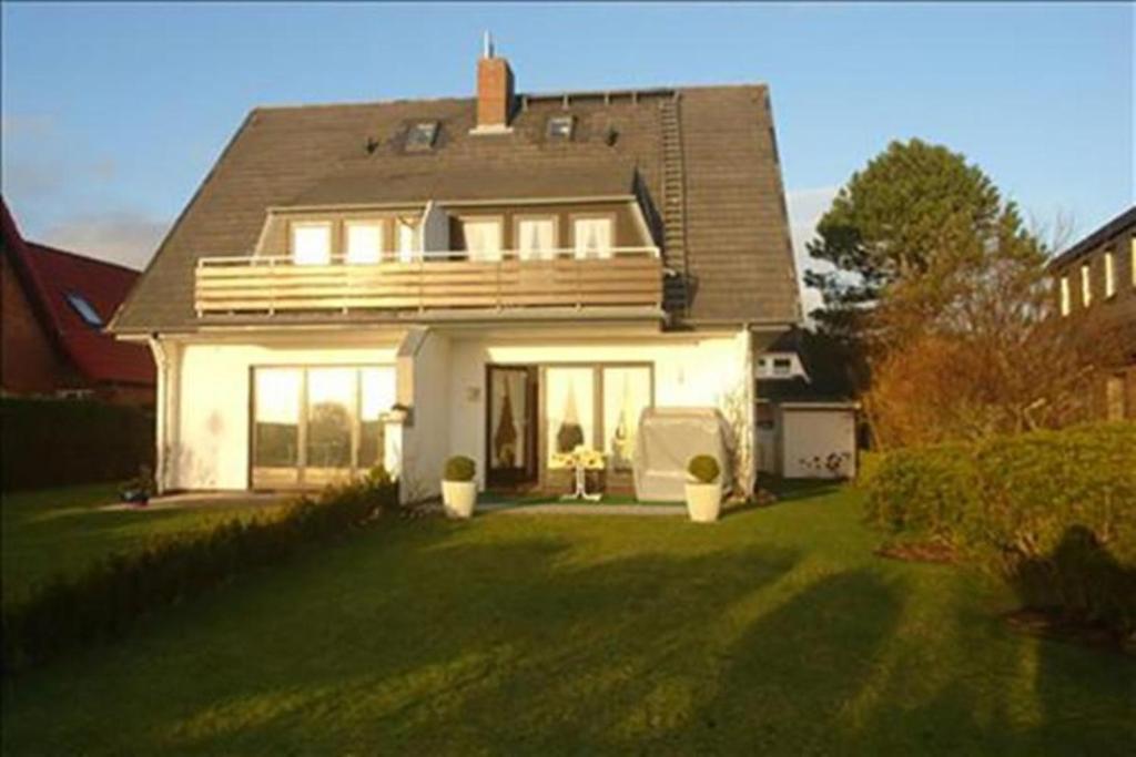 ein weißes Haus mit einer Terrasse auf einem Hof in der Unterkunft Apartment Westerheide in Braderup