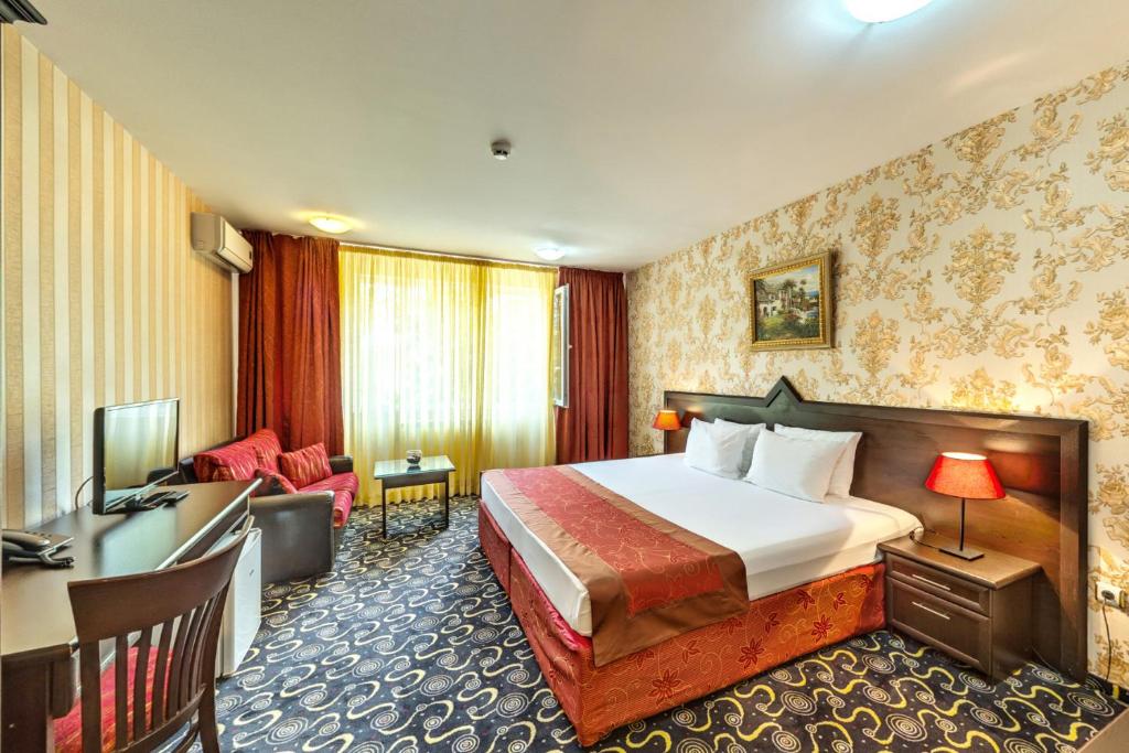 a hotel room with a bed and a desk at Hotel Montecito in Sofia