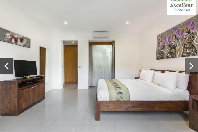a bedroom with a bed and a flat screen tv at Villa Kamar Madu in Seminyak