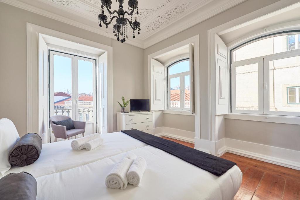 sypialnia z dużym białym łóżkiem i oknami w obiekcie Casa Portuguesa Combro w Lizbonie