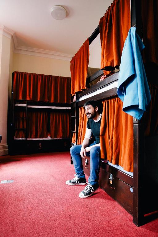 a man is sitting in a bunk bed at Palmers Lodge Swiss Cottage in London