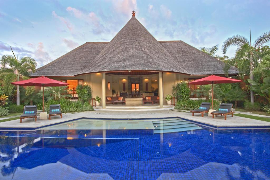 Villa con piscina frente a una casa en The Kunja Villa-Hotel en Seminyak