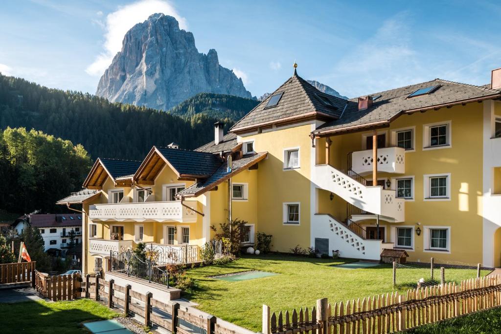 eine Reihe von Häusern vor einem Berg in der Unterkunft Alpenhotel Plaza in St. Christina in Gröden